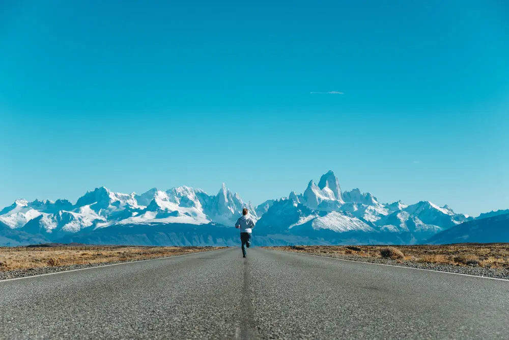Man running towards the mountains on a empty road. 